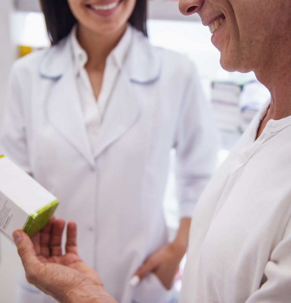 Beautiful young female pharmacist is suggesting a medication to a client at the pharmacy and smiling